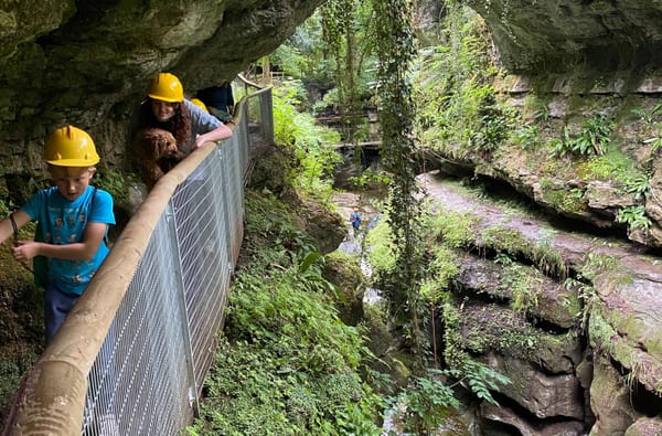Family exploring the ravine and gorge at How Stean Gorge with hard hats scrambling under rocks copy